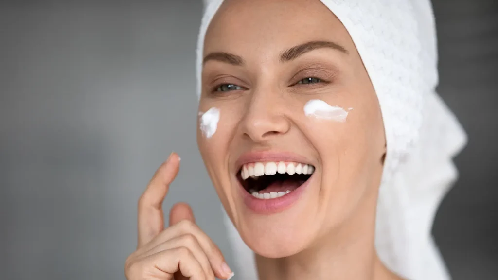 A woman happily doing her skincare routine.