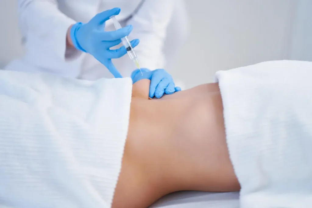 A medical professional administering an injection into a patient's abdomen.