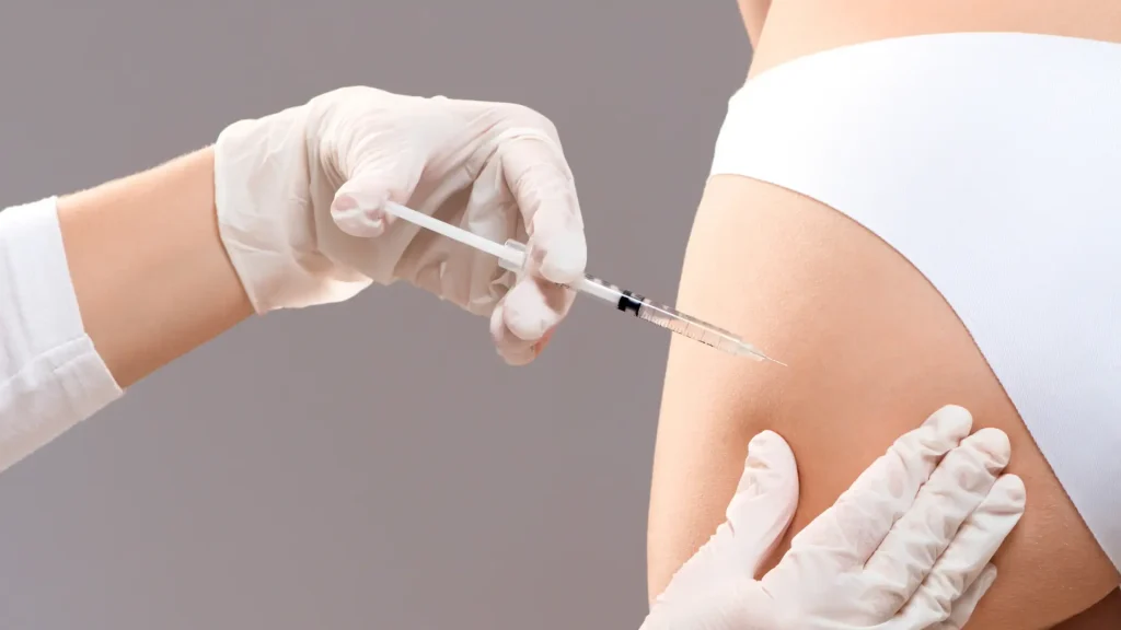 A medical professional administering an injection into a patient's buttocks to treat cellulite.