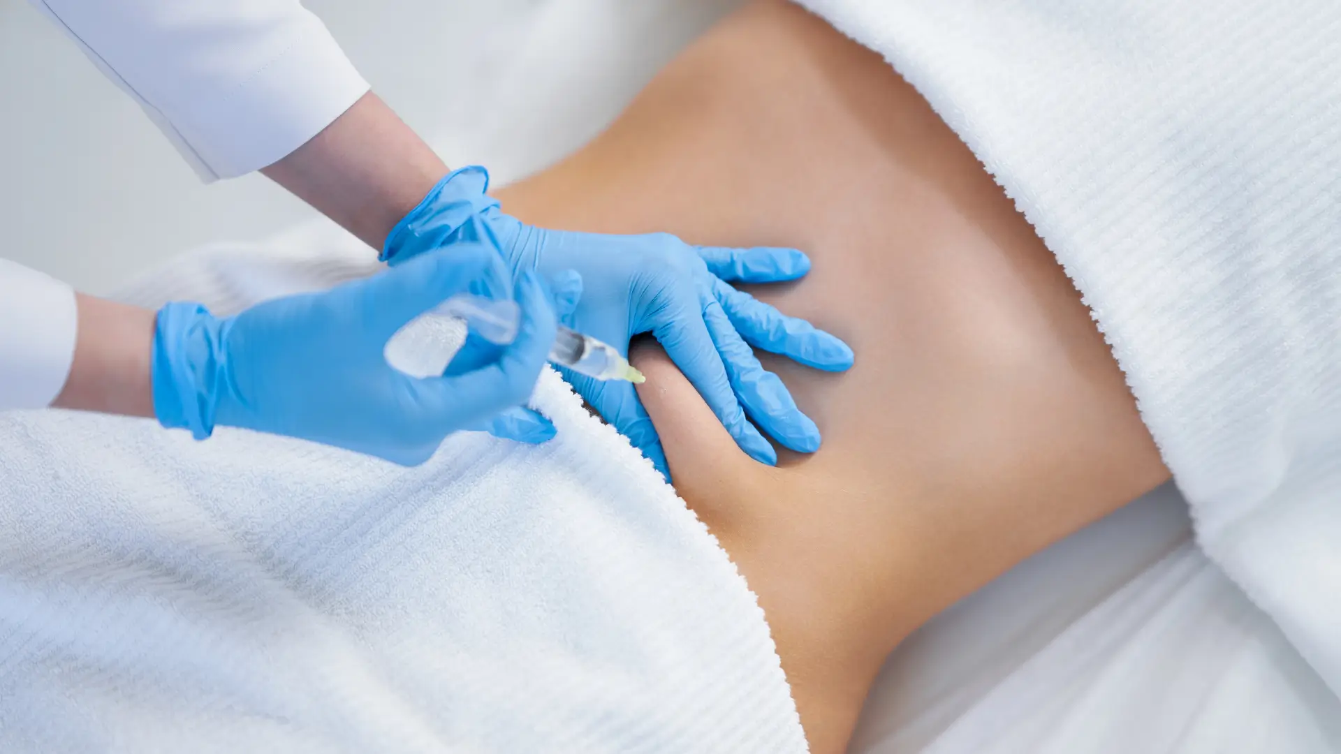 An individual receiving an injection into their abdomen region.