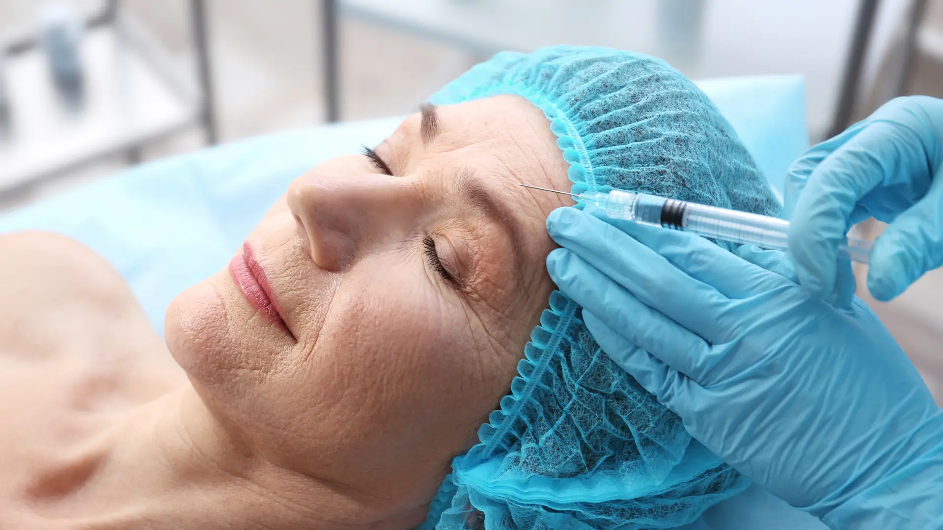 An older woman receiving a hyaluronic acid injection for their forehead wrinkles.