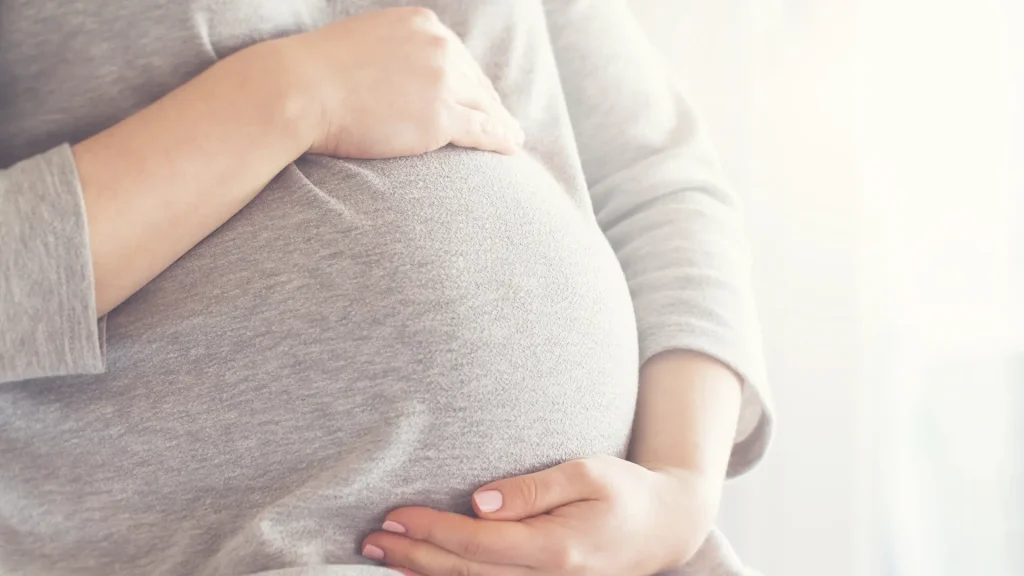 A woman holding their baby bump.