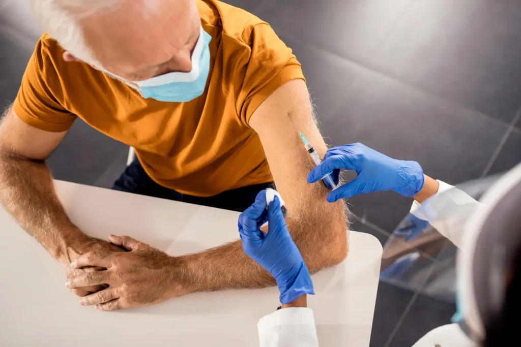 An older man receiving an injection in their upper arm.