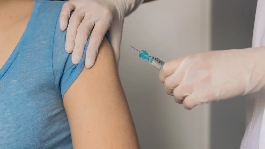 A medical professional administering an injection into a patient's upper arm.