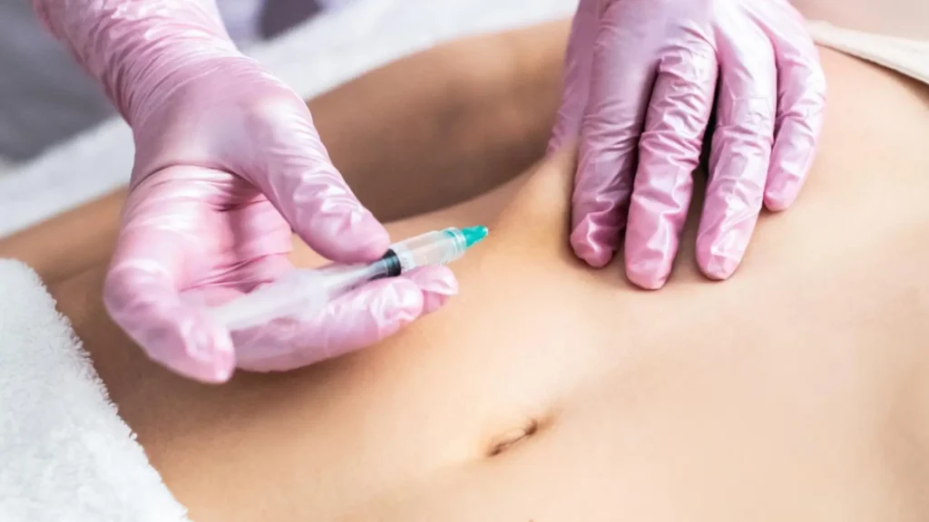A medical professional administering an injection into a patient's abdomen.
