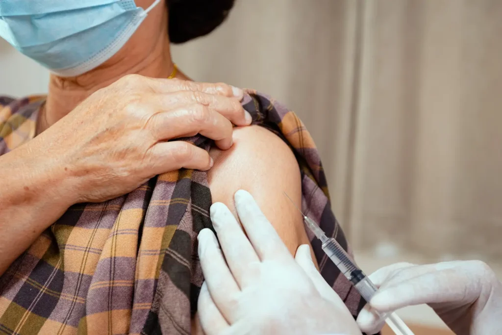 An older individual receiving an injection into their upper arm.
