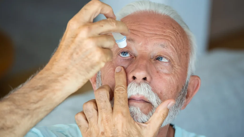 An older individual applying a eye drop medication.