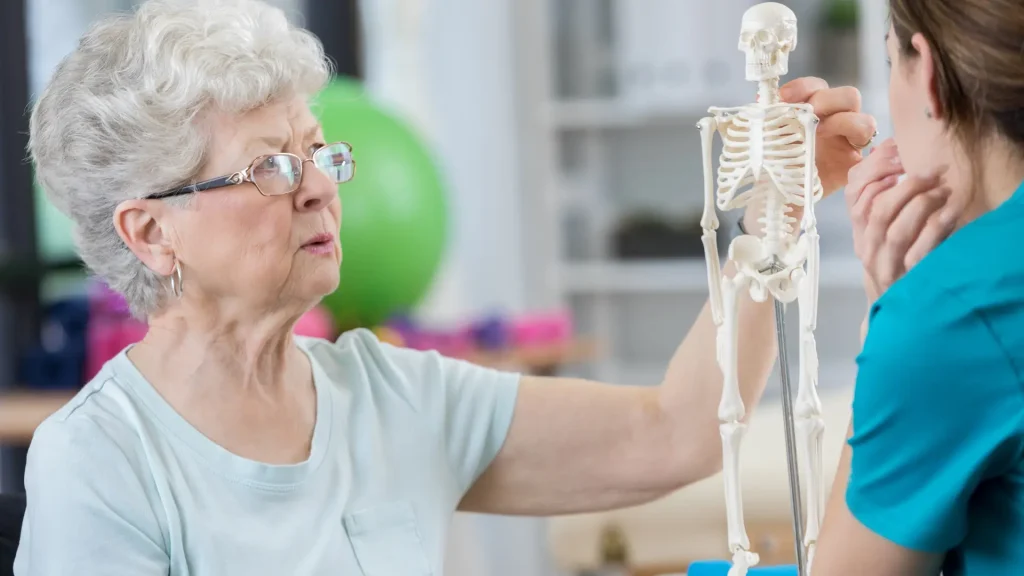 An older individual discussing their osteoporosis symptoms with a medical professional.