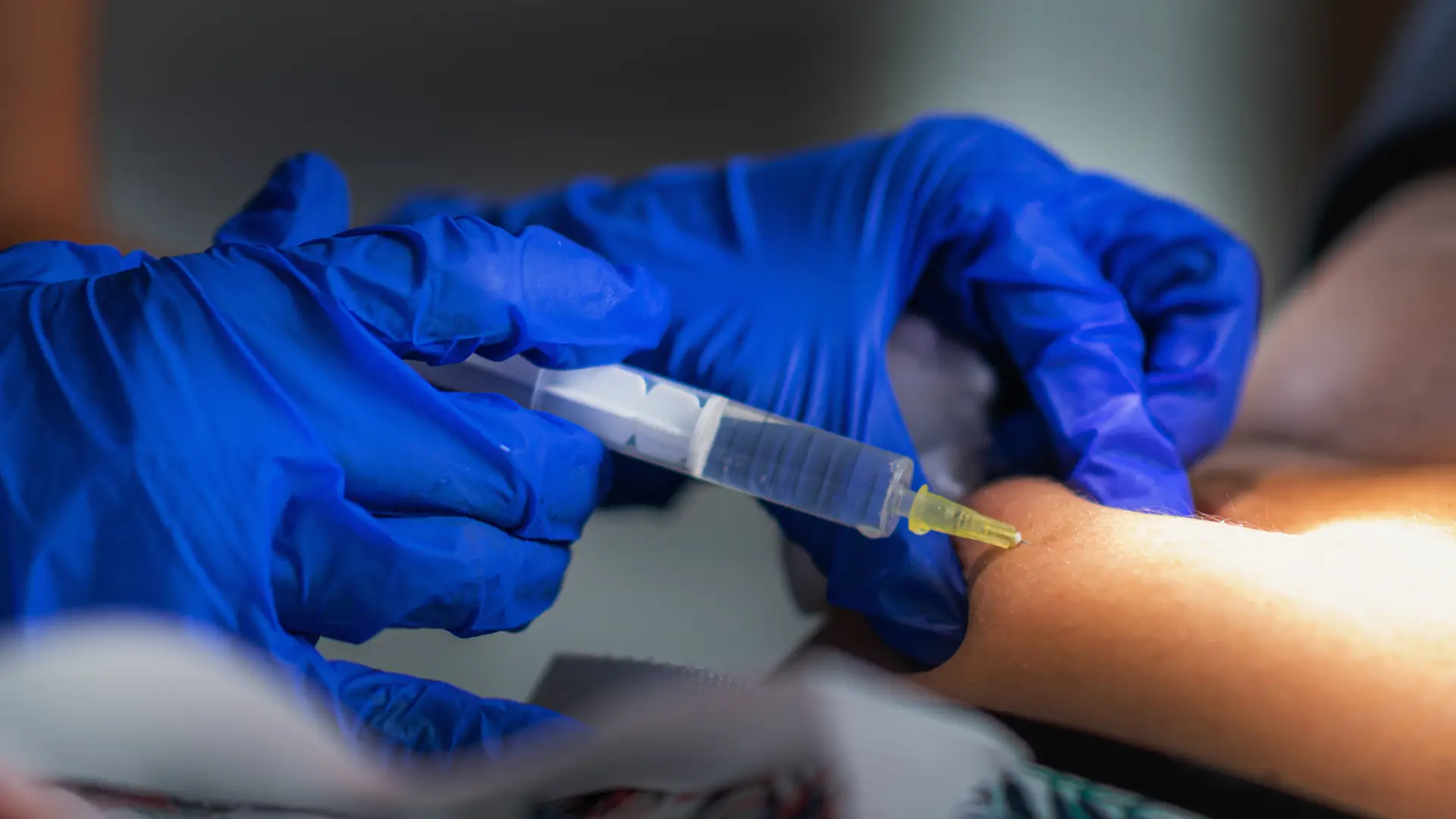 A medical professional administering an injection into a patient's abdomen.