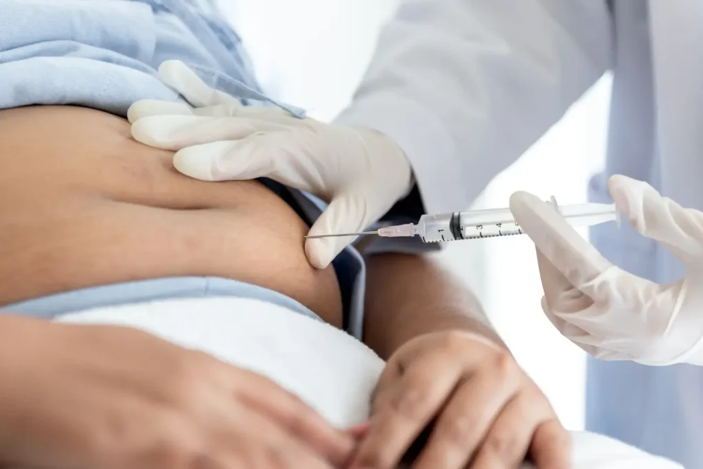 An individual receiving an injection in their abdomen region.