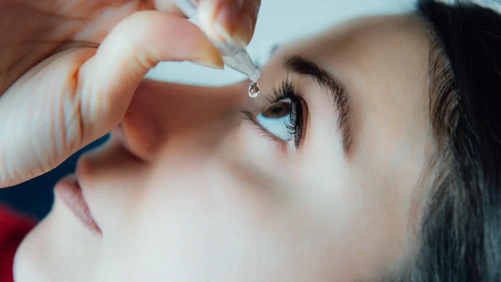 An individual applying an eye drop.
