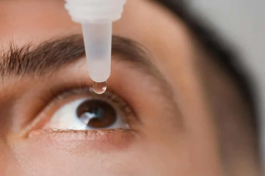 An individual using an eye drop for their eyes.