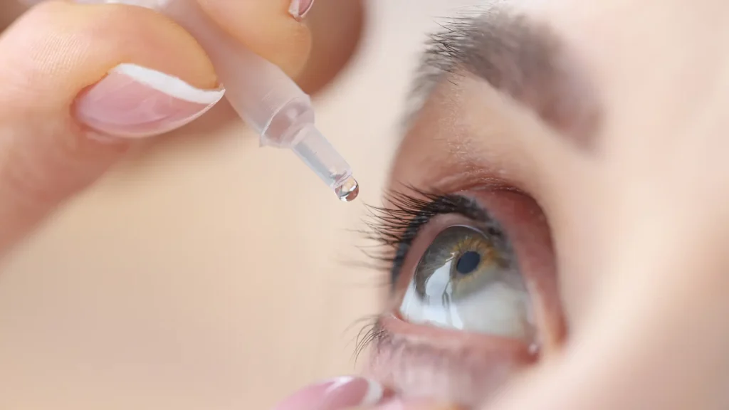 An individual applying an eye solution in their eye.