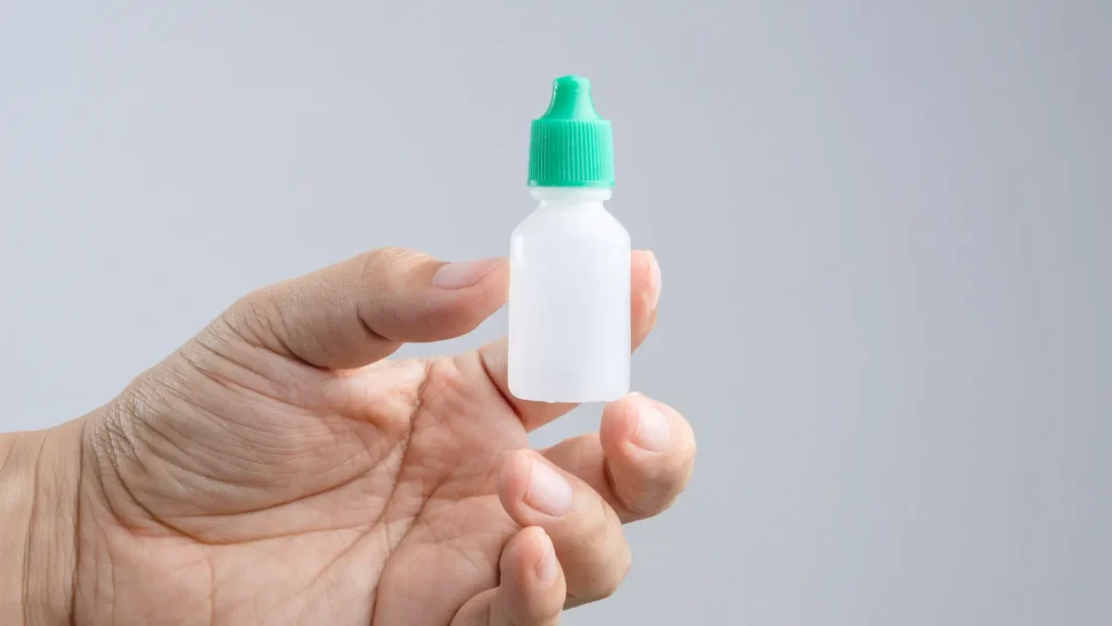 An individual working an eye drop bottle.