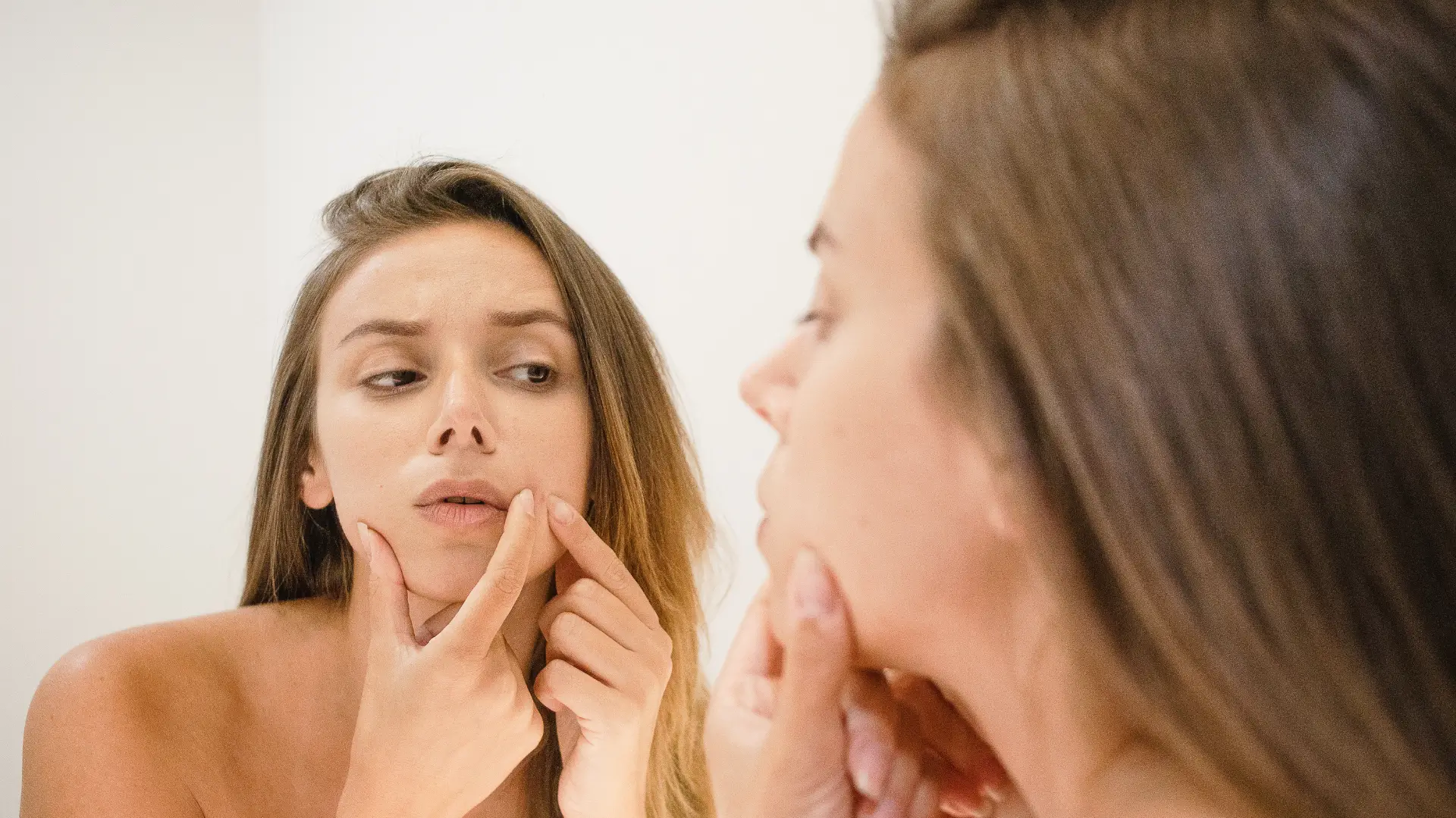 An individual checking their face in the mirror.