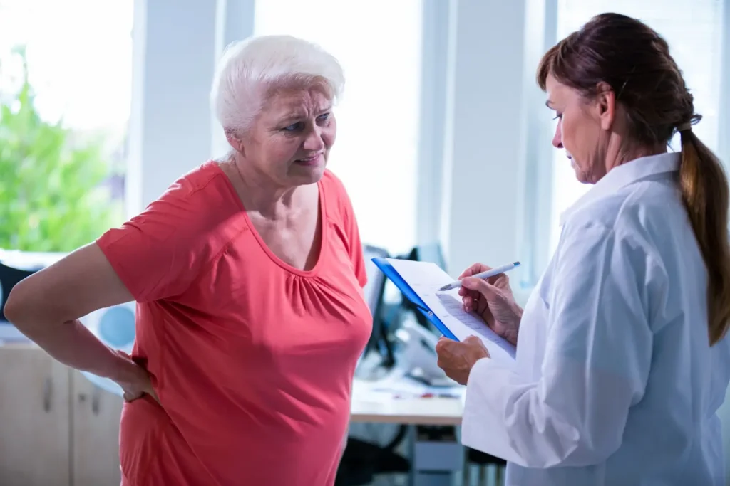 An older individual consulting a medical professional about their back pain.