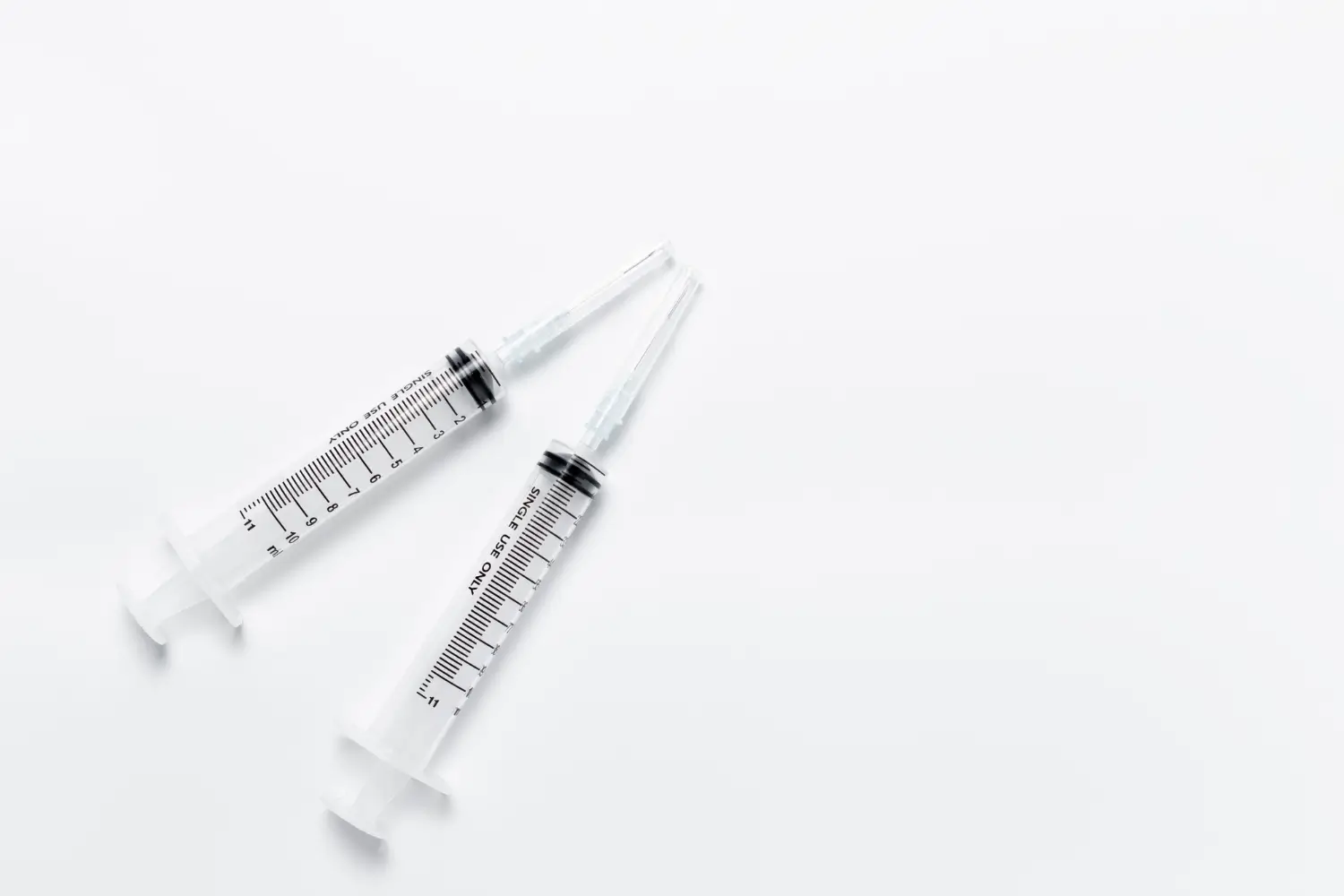Two medical syringes on a surface.