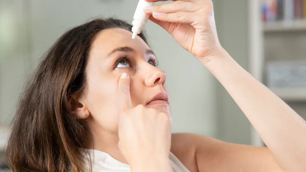 An individual applying an eye drop.