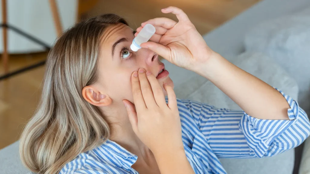 An individual applying eye drops.