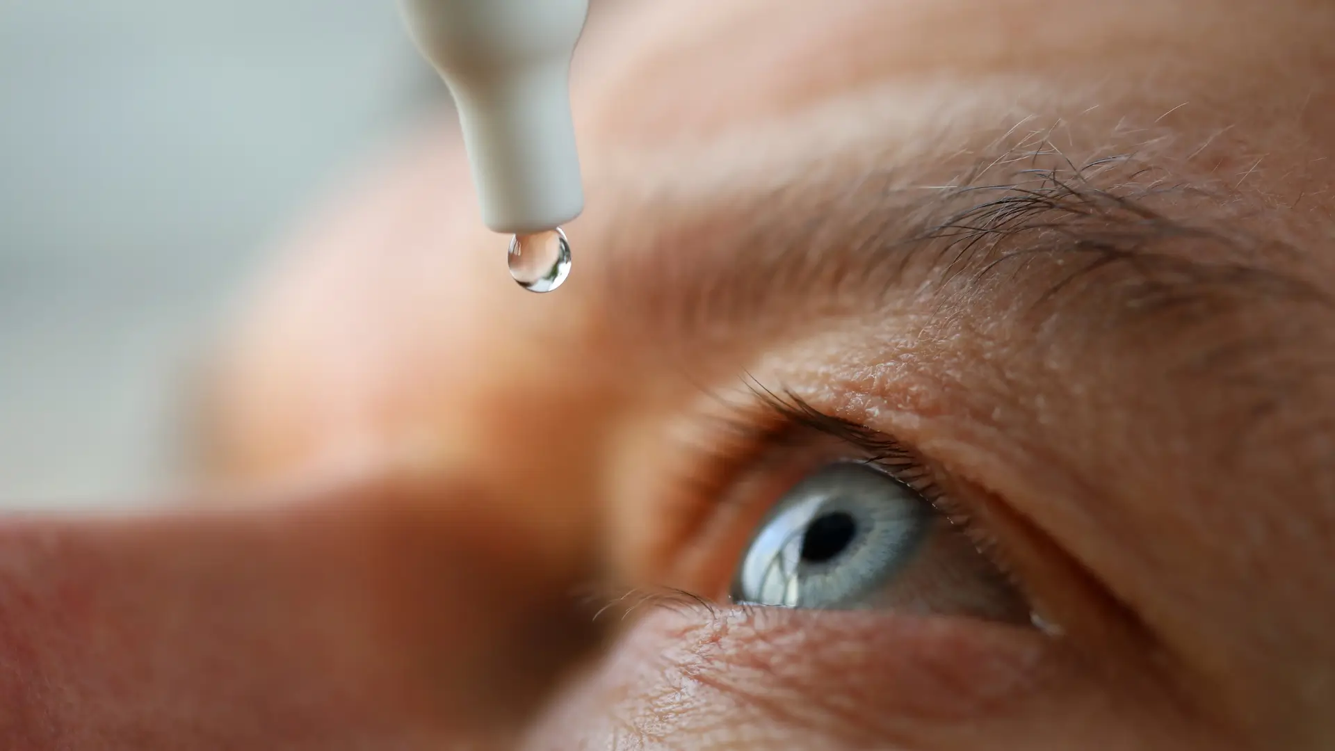 An individual applying eye drops.