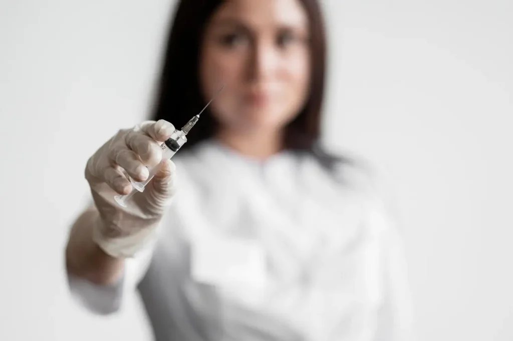 A medical professional holding a medical injection.