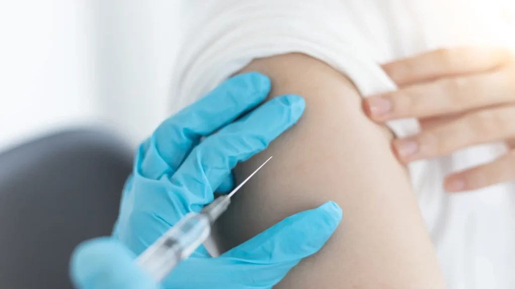 A medical professional administering an upper arm injection to a woman.
