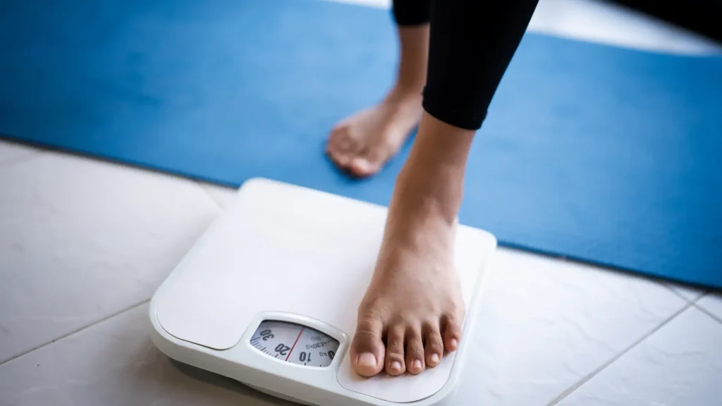 An individual stepping on an electronic weight scale.