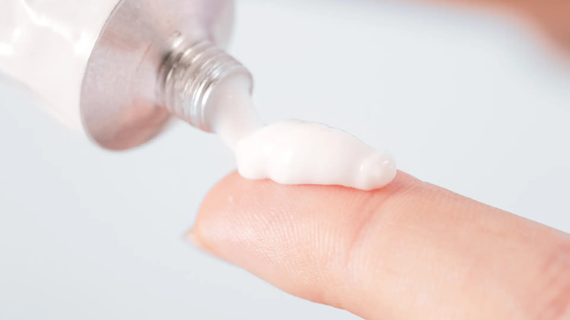 A medicine cream on an individual's finger.