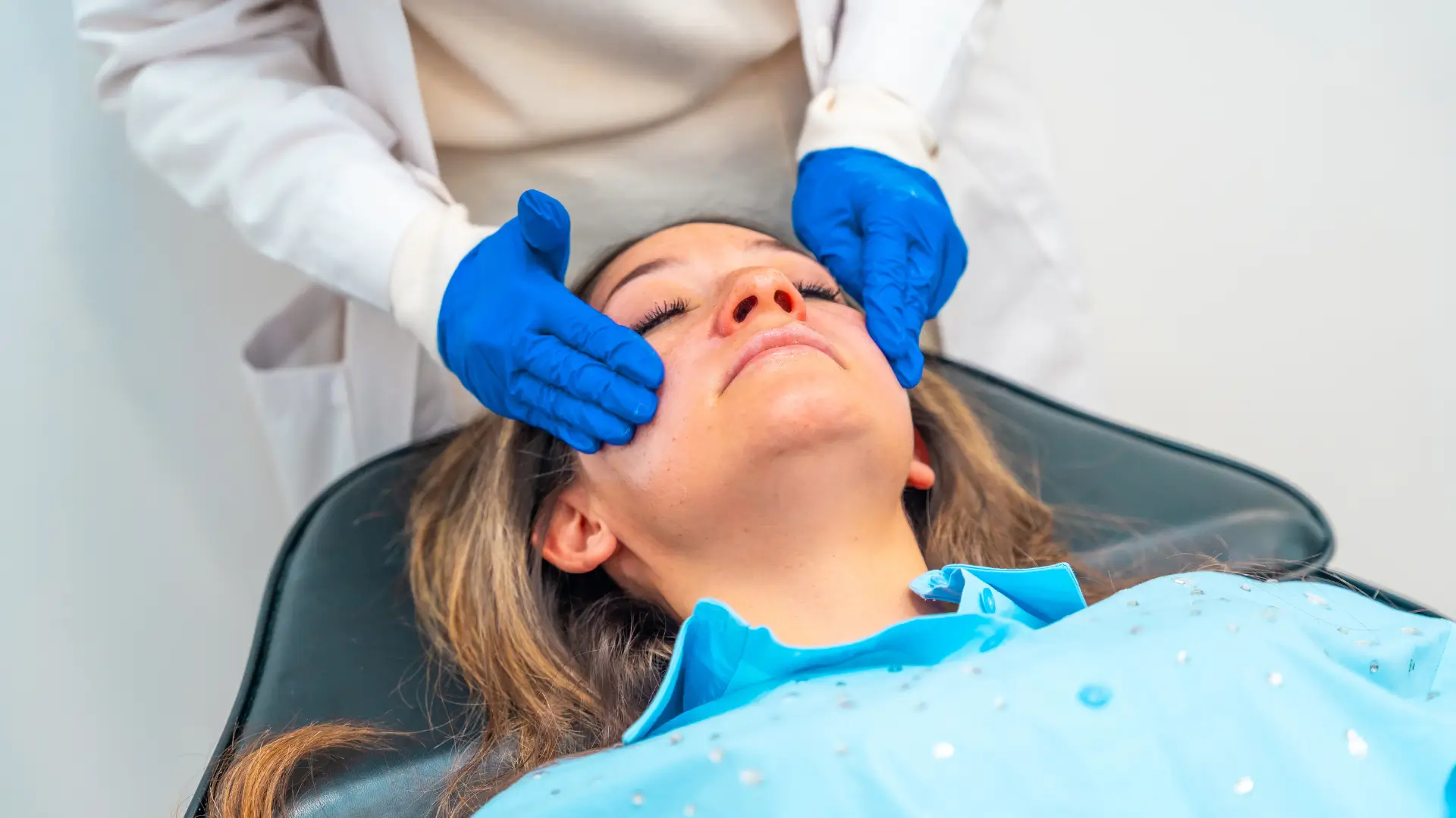 A medical professional applying nubing cream on the patient's facial region.