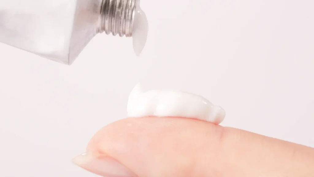An individual with a small amount of cream on their finger.