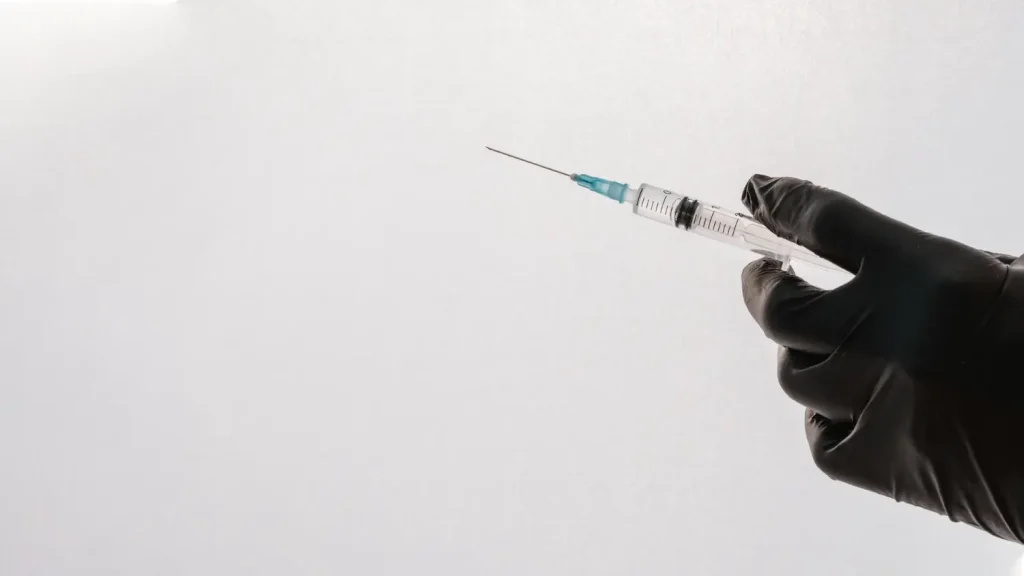 A medical professional holding a medical syringe.