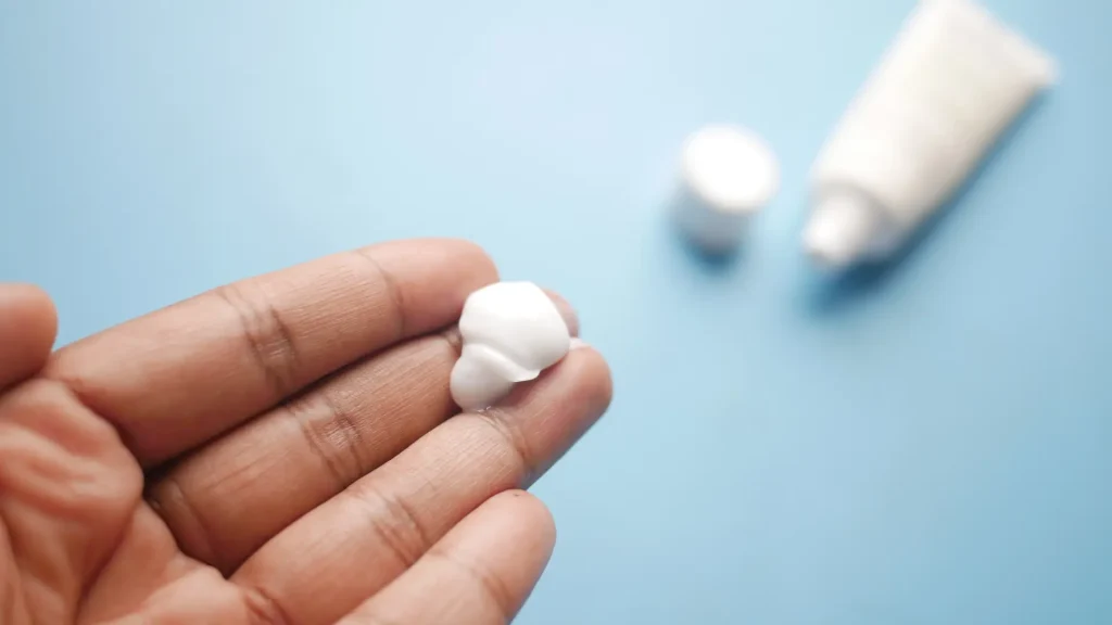 An individual holding an ample amount of cream on their hand.