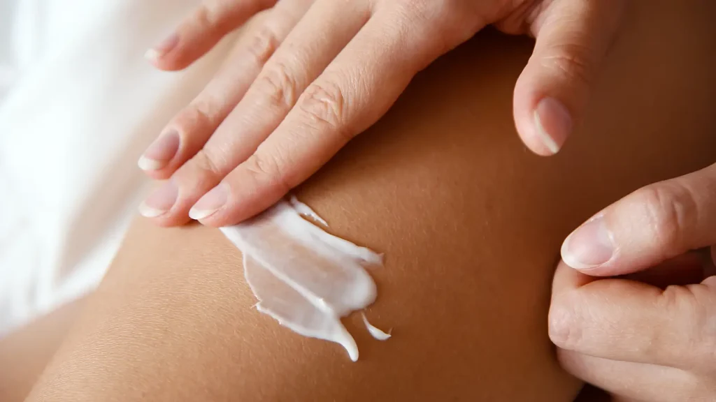 An individual applying a cream on their skin.