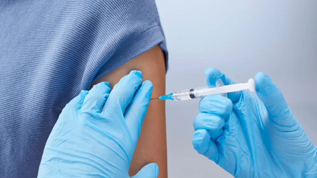 A medical professional administering an injection to a patient's upper arm.