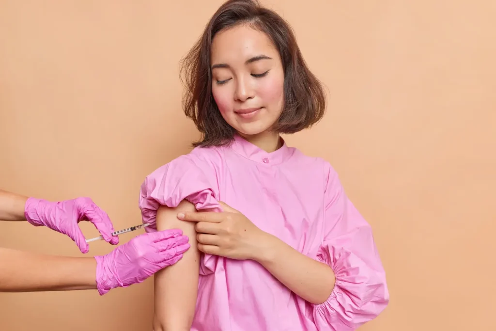 An individual receiving an injection shot on their upper arm.