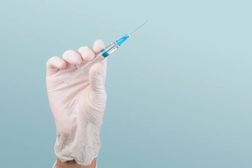 A medical professional holding a medical syringe.