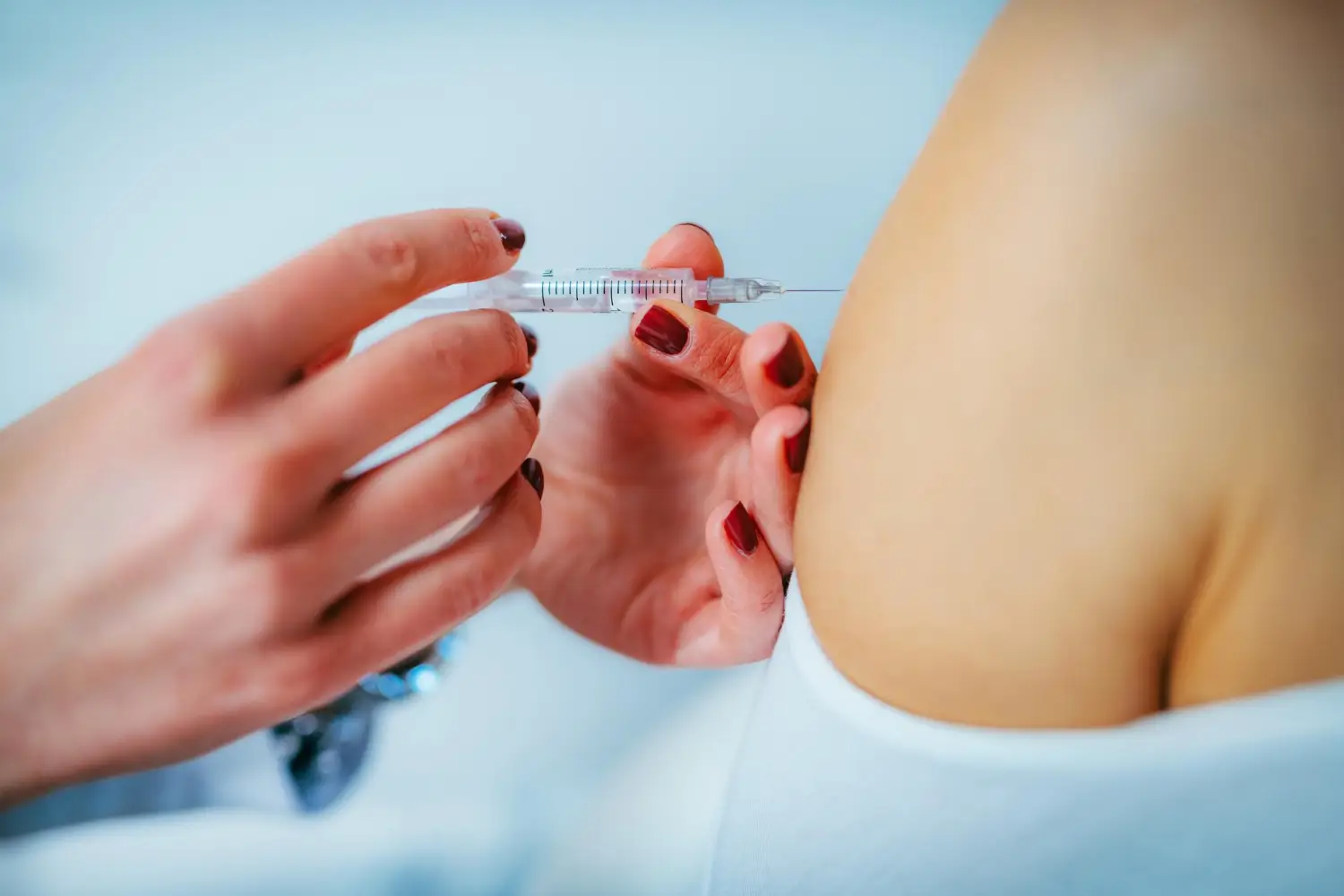 A medical professional administering an injection into a patient's upper arm.