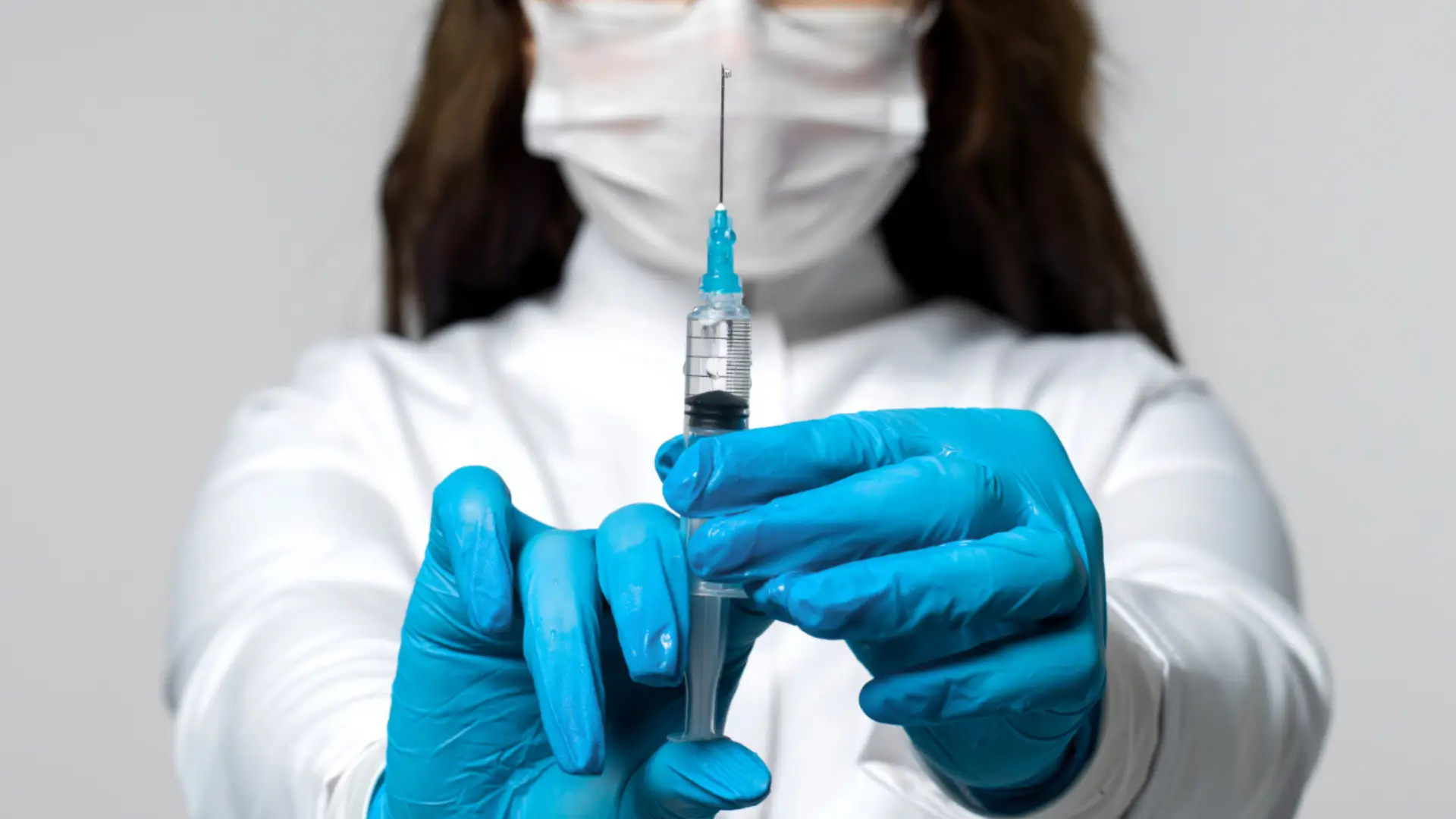 A medical professional holding a medical syringe.