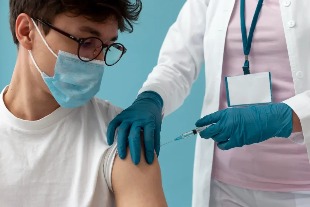 A male individual wearing a mask receiving an arm injection.