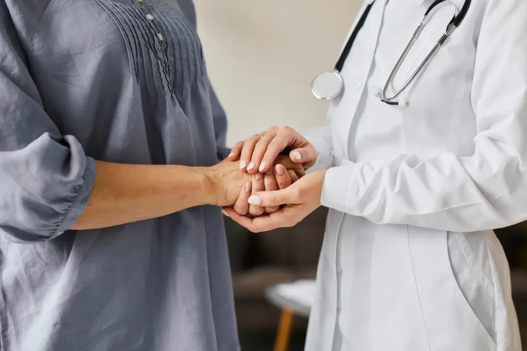 A medical professional holding a patient's hand, offering support.