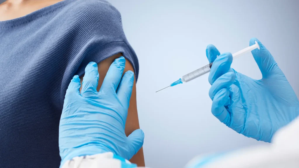 A female patient receiving an injection on their upper arm.