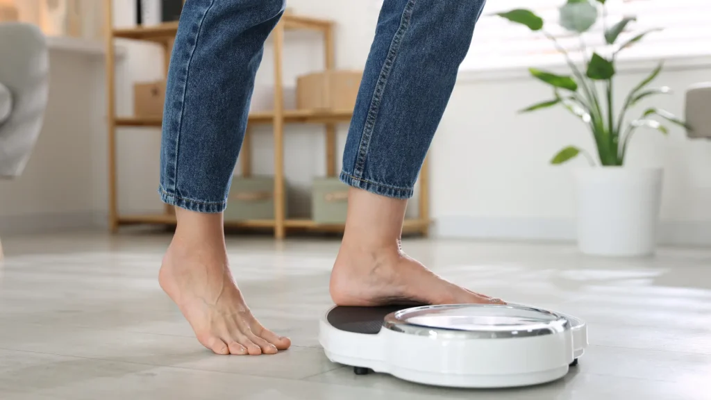 An individual checking their weight on a scale.