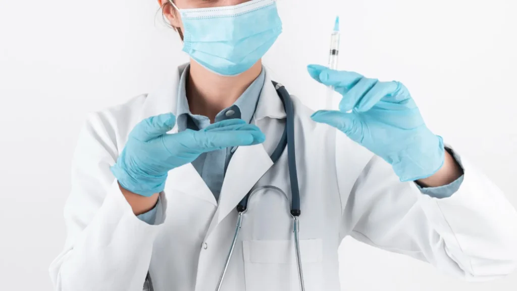 A medical professional holding a medical syringe.