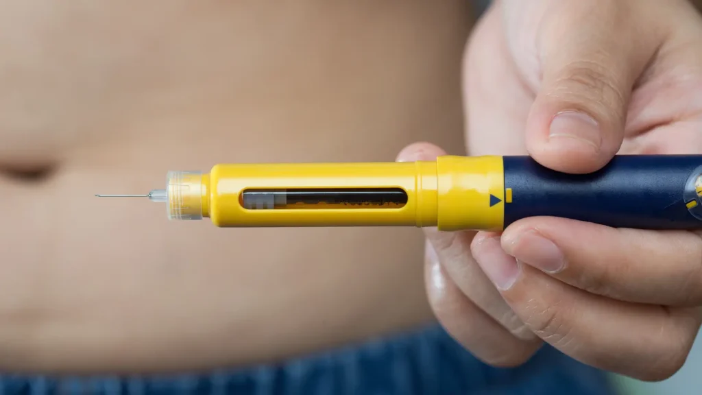 A close-up shot of an injection pen before administering to the stomach area.