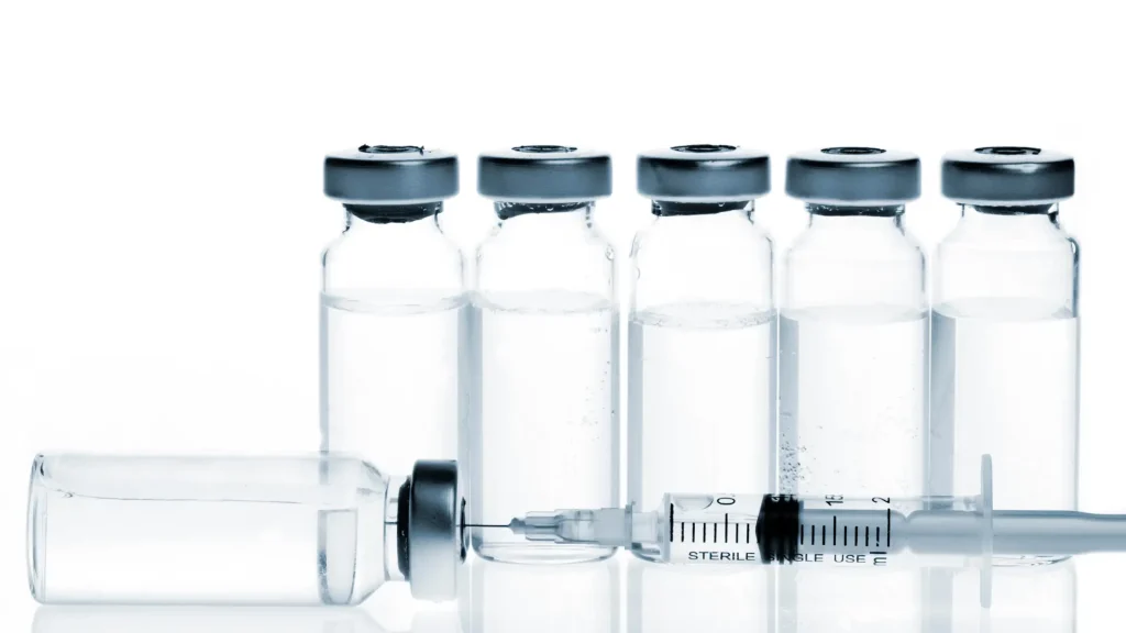 Vials lined up with a medical injection injected in a vial.