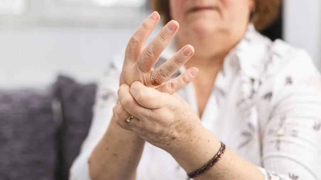 An individual massaging their hands when the symptoms of rheumatoid arthritis occur.