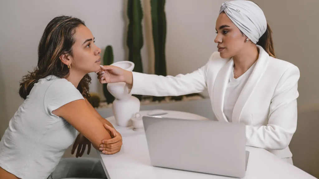 An esthetician evaluating a female patient's facial region before prescribing a treatment.