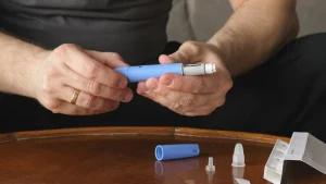An individual preparing their autoinjector pen for their Ozempic injection administration.
