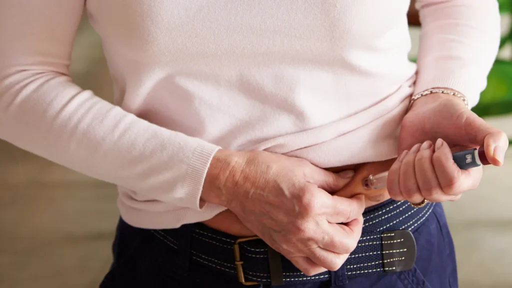 An individual using a self-injection pen to their abdomen.