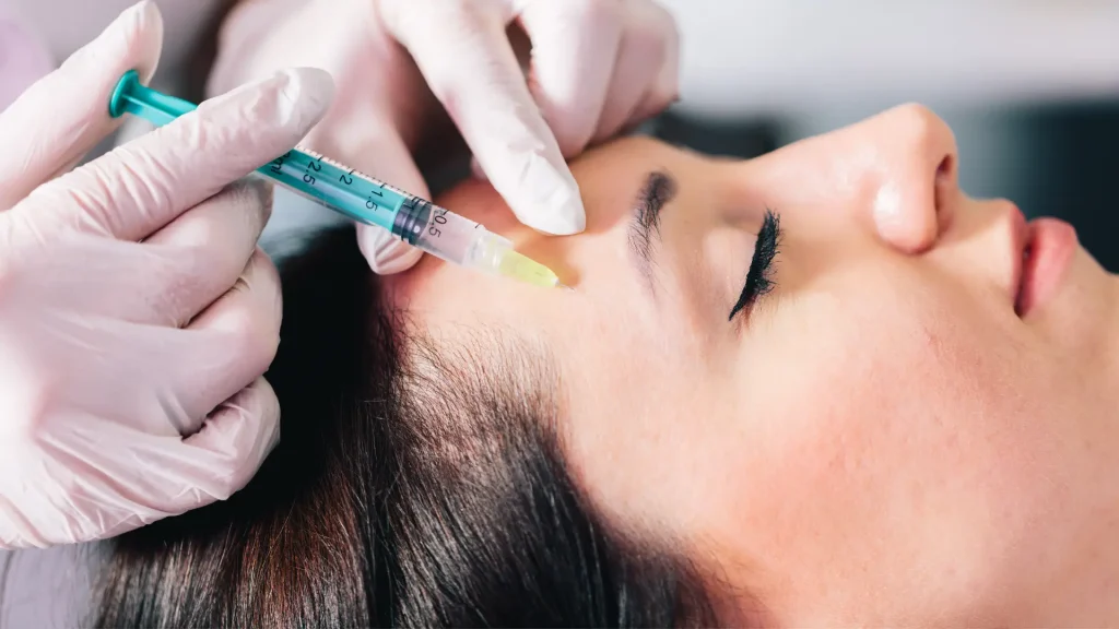 An individual undergoing an injection treatment for their upper face region.